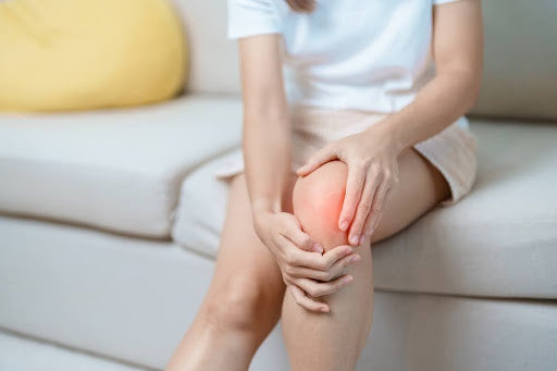 A woman experiencing sudden knee pain without injury.